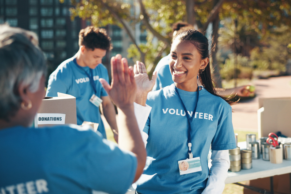 Outdoor, volunteer and friends with high five, help and goals for donations, charity and support. 