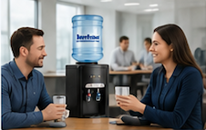 Water dispenser for office. Two co-workers talking and drinking water in front of a water dispenser